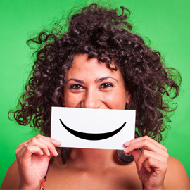 Woman holding a smile sign over her mouth