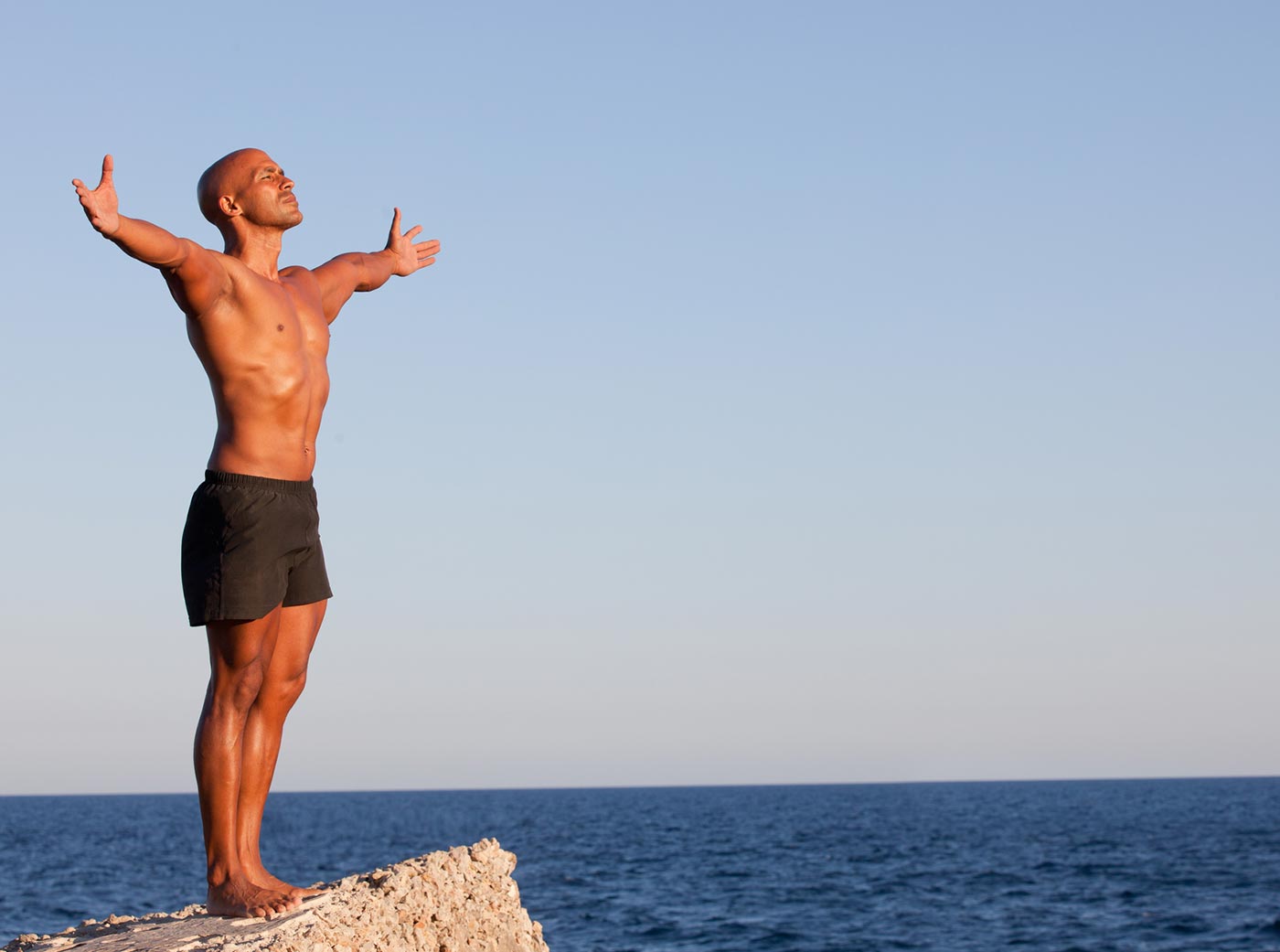 Man closing his eyes lifting his arms in the air and breathing the air